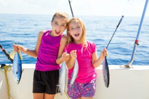 two kids holding up fish while fishing
