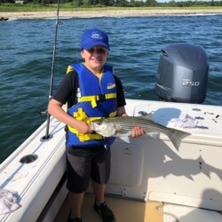 little boy holding a fish during a fishing charter