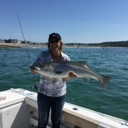 woman on a fishing charter holding a striper